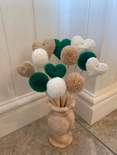 a vase filled with white and green pom - poms on top of a counter