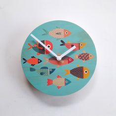 a clock with fish painted on it sitting on a white surface, showing the time