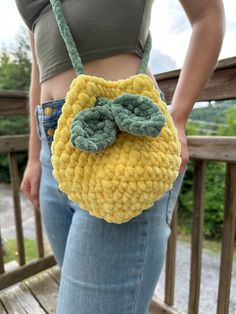 a woman is holding a crocheted purse with a bow on the front and side