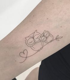 an owl tattoo on the arm with two hearts and leaves in it's center