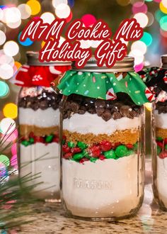 three mason jars filled with cookies and candy on top of a counter next to christmas lights