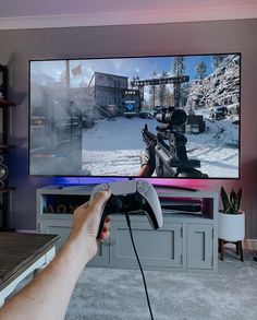 a person holding a video game controller in front of a flat screen tv