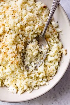 a white bowl filled with rice and a spoon