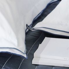 two white books sitting on top of a bed next to pillows