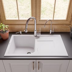 a kitchen sink sitting under a window next to a potted plant