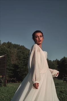 a woman in a white dress is standing outside