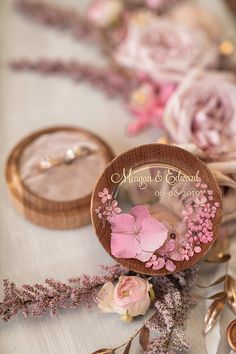 two wedding rings sitting on top of a table next to pink flowers and other items