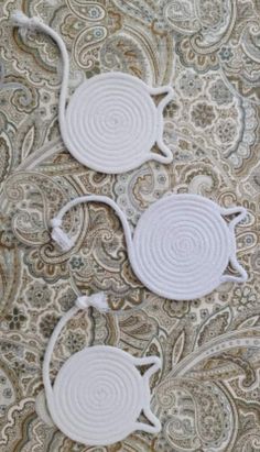 two white decorative wall hangings on a paisley print fabric with swirly circles in the middle