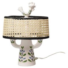 a table lamp with a white base and black shade on the bottom, decorated with green leaves