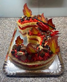 a cake that has been decorated with leaves and chocolates on it, sitting on a glass platter