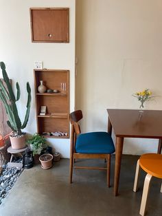 two chairs and a table in a room with a cactus on the floor next to it