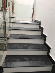 a set of black and white stairs with glass handrails