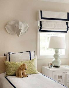 a dog sitting on top of a white bed in a bedroom next to a window