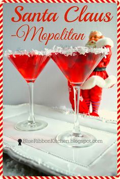 two glasses filled with red liquid sitting on top of a white tablecloth next to santa clause