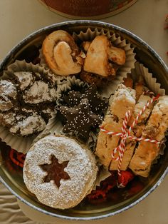 an assortment of pastries and cookies in a metal bowl on a table with candy canes