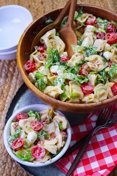 a wooden bowl filled with pasta salad next to another bowl