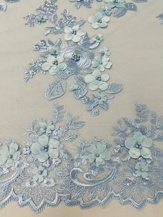 an embroidered fabric with blue flowers and leaves on white background, closeup view from the bottom