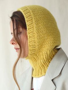 a woman wearing a yellow knitted hat with a hood on her head and jacket over her shoulders