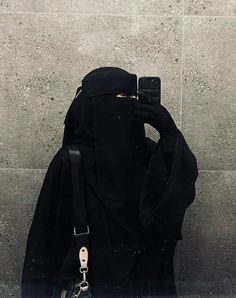 a person with a cell phone in their hand taking a selfie while wearing a black outfit