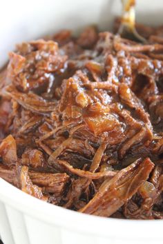 a white bowl filled with shredded meat on top of a table