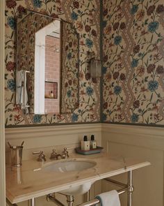 a bathroom sink sitting under a mirror next to a wall mounted soap dispenser