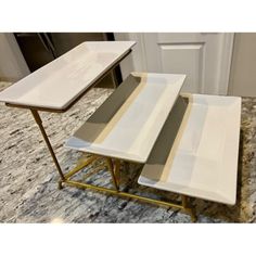 three white trays sitting next to each other on top of a marble countertop