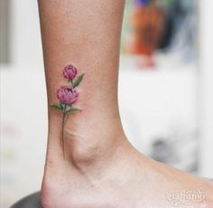 a small pink flower on the ankle is shown with green leaves and flowers around it