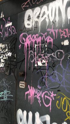 graffiti on the side of a building in front of a door that has writing all over it