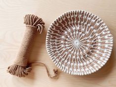 a white and brown basket sitting on top of a wooden table next to a rope