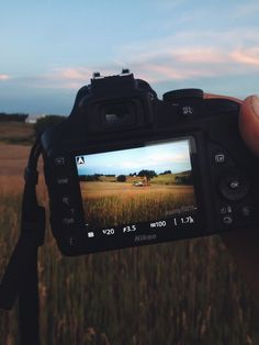 a person holding up a camera in front of a field