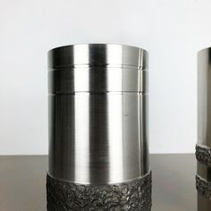 two silver vases sitting next to each other on a table