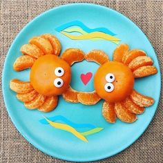 two oranges with googly eyes are on a plate that has an octopus and fish design