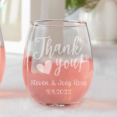 two wine glasses sitting on top of a table with pink liquid in the bottom and white lettering that says thank you