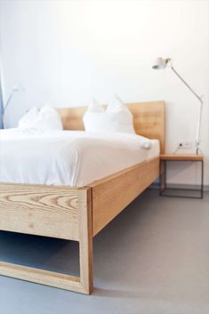 a wooden bed with white sheets and pillows