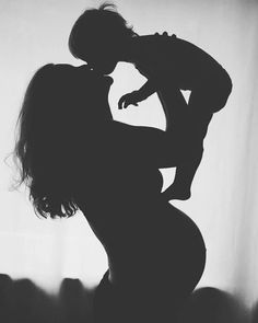 the silhouette of a woman holding a baby in her arms