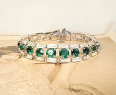 "Offering an absolutely stunning high quality vintage Art Deco emerald green and clear crystal rhinestone Flapper bracelet perfect for the Bride. The rhodium plated bracelet is made up of a central row of rich emerald green claw set round cut sparkly crystal rhinestones.  The stones in the middle are larger and then get smaller in size towards the clasp.  Flanking the emerald stones above and below are SO 1920s baguette cut clear sparkly crystal rhinestones.  You won't believe the sparkle in thi Art Deco Emerald, Mixed Metal Bracelets, Art Deco Hair, Vintage Rhinestone Jewelry, 1920s Wedding, Geometric Bracelet, Art Deco Bracelet, Emerald Bracelet, Rhinestone Art