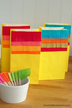 colorful paper bags and toothbrushes in a white bowl on a wooden table next to a cup