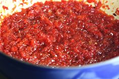 a blue pot filled with red sauce on top of a stove