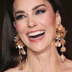 a smiling woman wearing large gold earrings