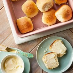 rolls and butter are sitting on plates next to a baking pan with bread in it