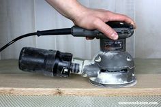 a person using a sander on top of a piece of wood with one hand