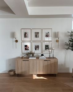 a living room with pictures on the wall and a table in front of it,