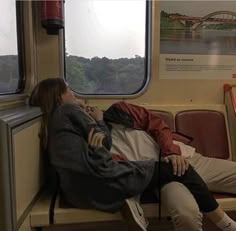 two people sitting on a train next to each other and looking out the window,