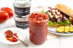 a jar filled with ketchup sitting on top of a table next to plates of food