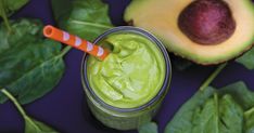 an avocado smoothie in a glass with a striped straw next to it