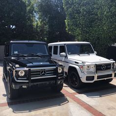 two mercedes benz trucks parked next to each other in front of some trees and bushes