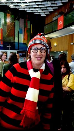 a woman wearing a red and black striped sweater with a knitted scarf around her neck