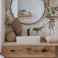 a bathroom with a sink, mirror and plants on the counter top in front of it