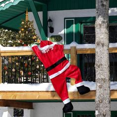 a santa clause suit hanging from a tree in front of a house