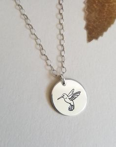 The Bird of Joy, the Hummingbird is a symbol of courage and determination. Wear this necklace as a reminder of your own courage within. A solid disc charm is hand engraved with the beautiful and profoundly meaningful Hummingbird. The circle charm measures 15 mm and floats on shimmering Sterling Silver, Gold Filled or Rose Gold Filled chain in your choice of length. Necklaces are all crafted with genuine materials not plated, so they will never peel, chip or flake off. Handcrafted with love, our Necklace With Round Pendant And Bird Design For Gifts, Round Pendant Necklace With Bird Design For Gift, Gift Jewelry With Bird Design Round Pendant, Bird Design Round Pendant Jewelry For Gifts, Bird Design Round Pendant Jewelry As Gift, Bird Design Round Pendant Jewelry Gift, Round Pendant Jewelry With Bird Design For Gift, Adjustable Bird Design Jewelry As Gift, Adjustable Bird Design Jewelry For Gifts